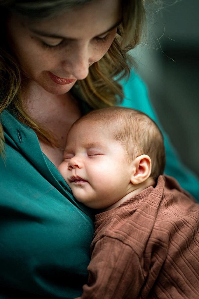 Newborn baby slapend bij mama op de borst.
