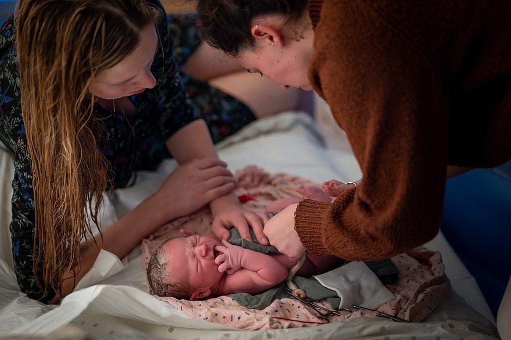 Pasgeboren baby wordt verzorgd door vroedvrouw.