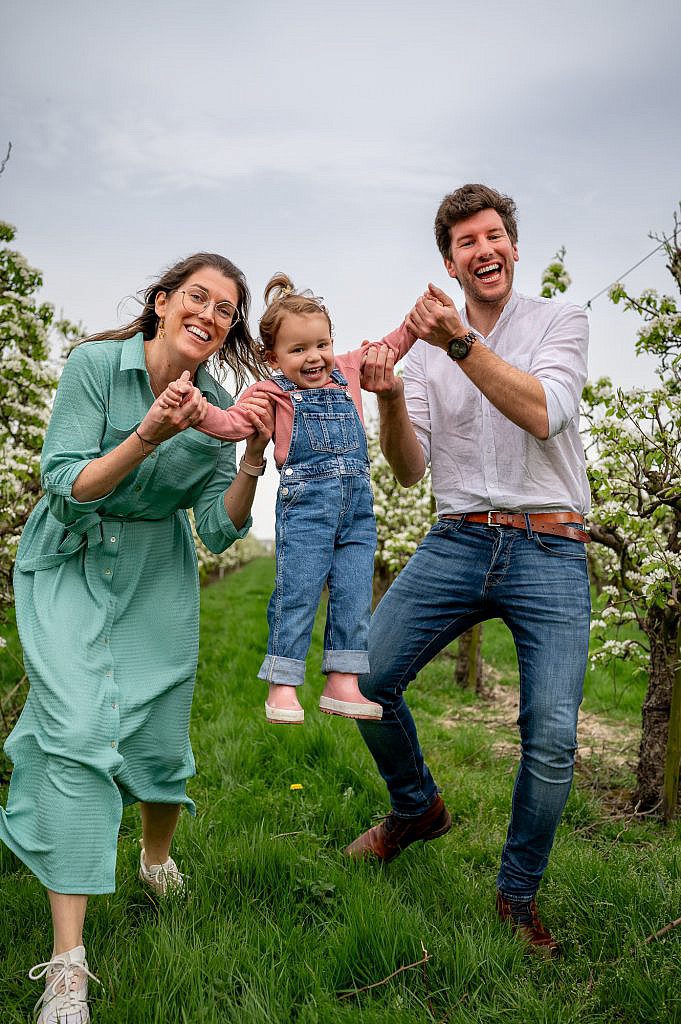 Fotoshoot gezin met mama en papa met peuter zwierend in de lucht.