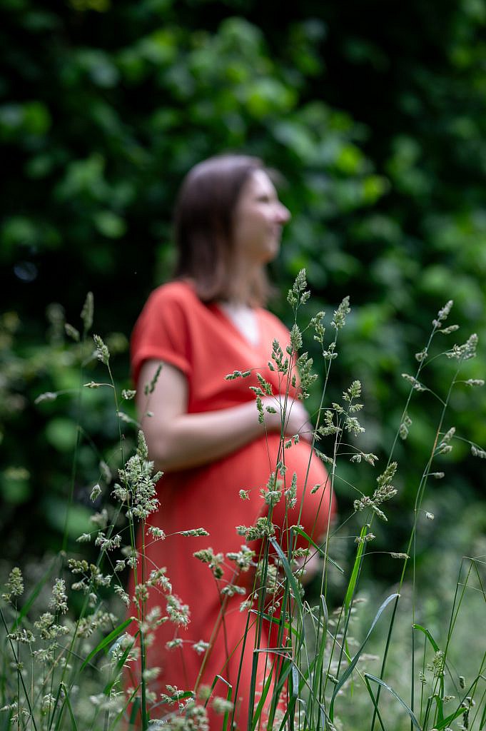 Zwangere vrouw achter het gras.
