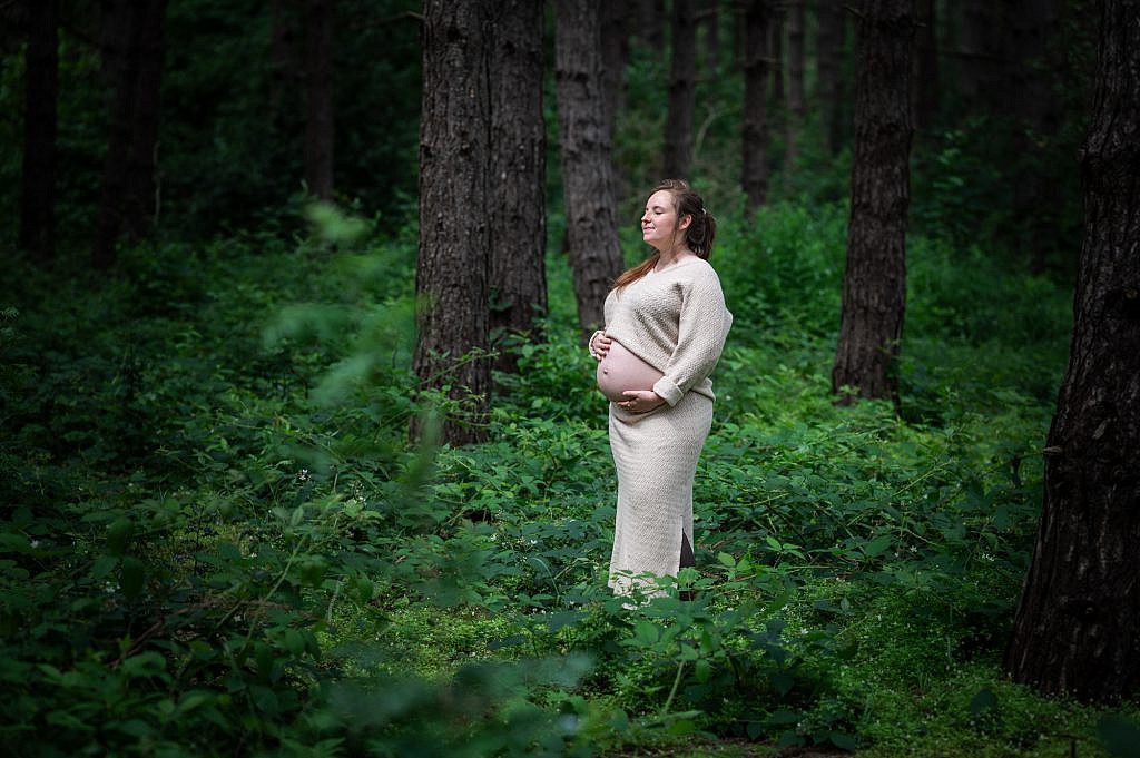 Zwangere vrouw met gesloten ogen in het bos.