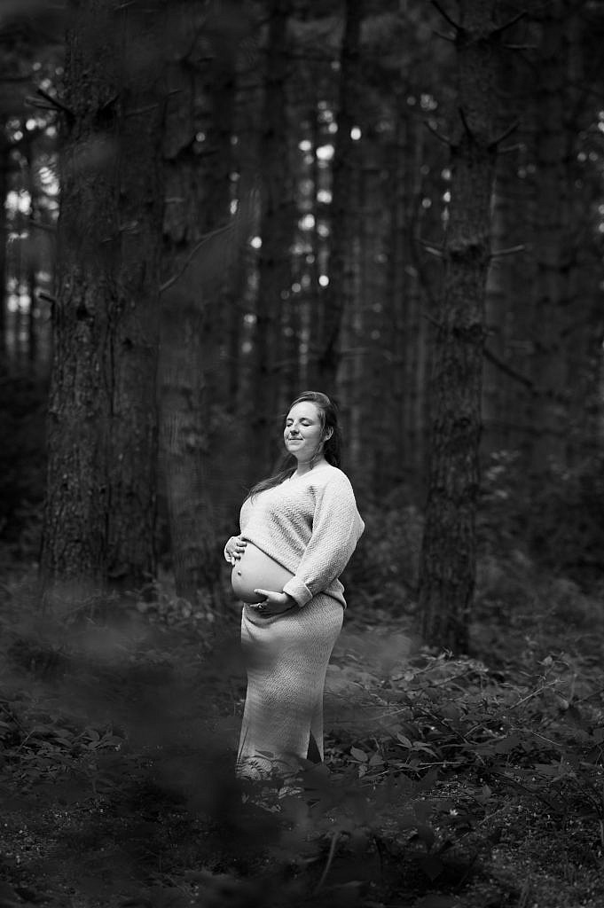 Zwangerschapsfotoshoot van zwangere vrouw in het bos in zwart wit.