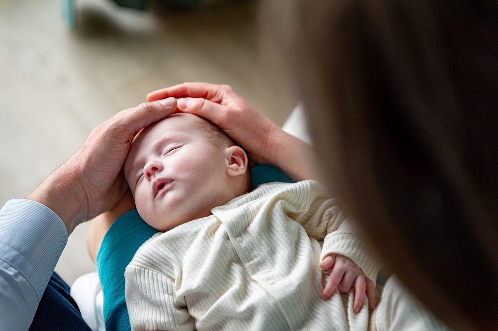 Newborn fotoshoot van slapende baby bij mama op schoot.