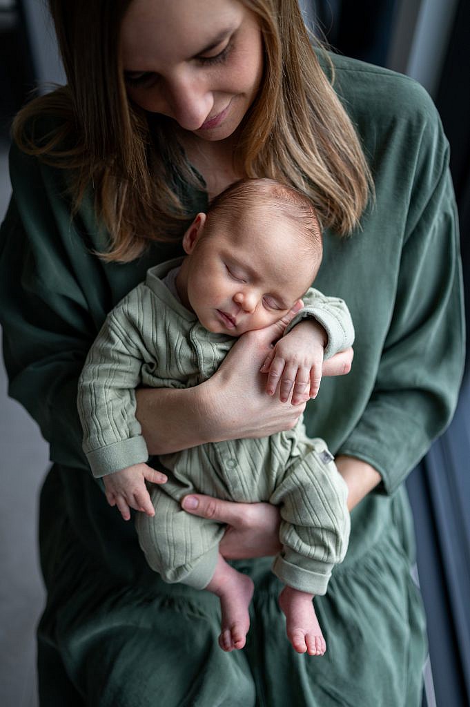 Newbornfotoshoot van slapende baby in de armen van mama.