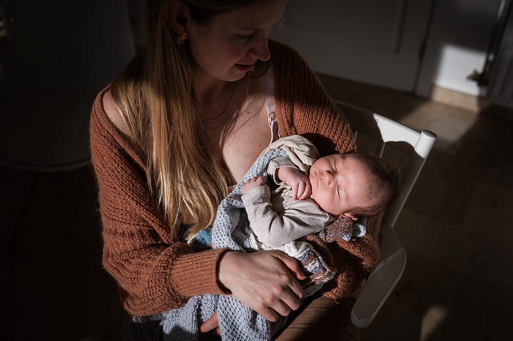 Newborn fotoshoot van slapende baby op mama haar arm.