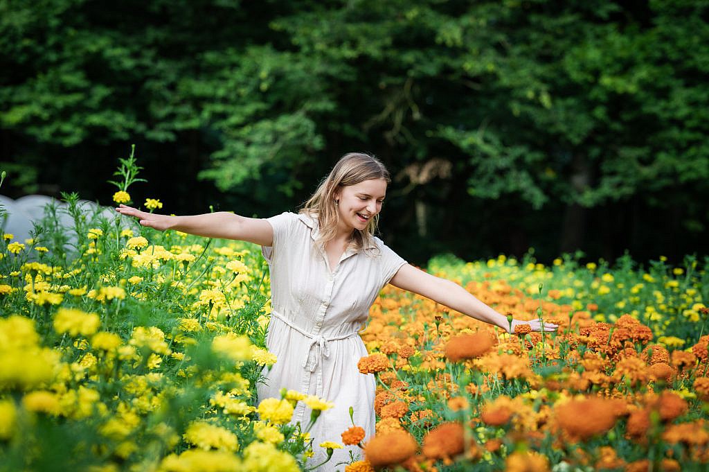 Jong meisje danst tussen gele en oranje bloemen.