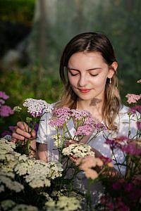 Jong meisje met gesloten ogen houdt roze en witte bloemen vast.