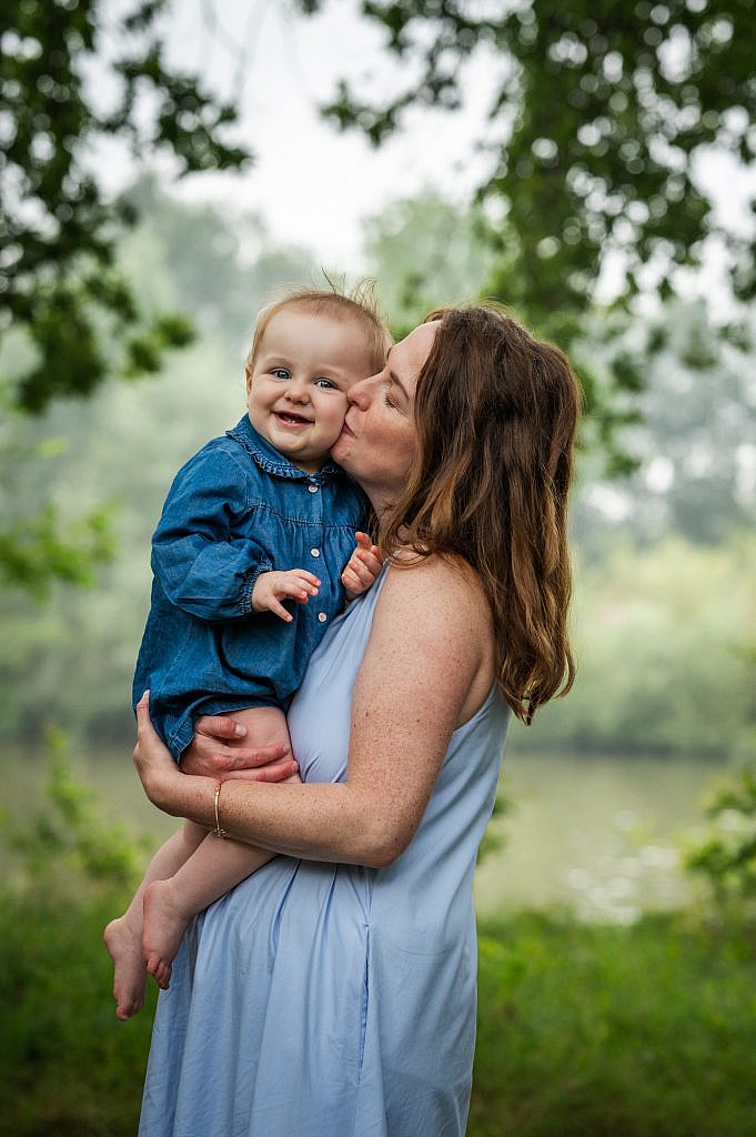 Gezin fotoshoot van lachende baby in de armen van mama.