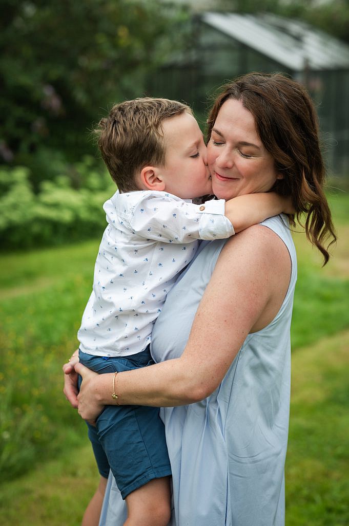 Fotoshoot gezin Lievegem van zoon die mama een zoen geeft in de tuin.