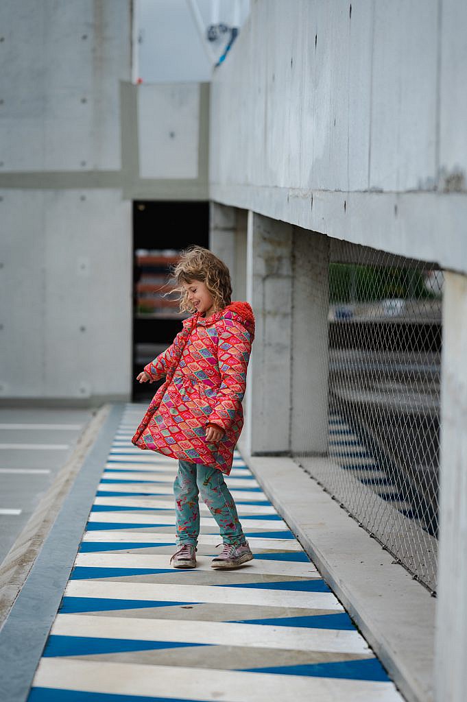 Communicant met rode jas op een soort zebrapad.