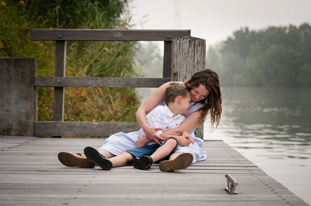 Gezin fotoshoot van mama al knuffelend met haar zoon aan het water.