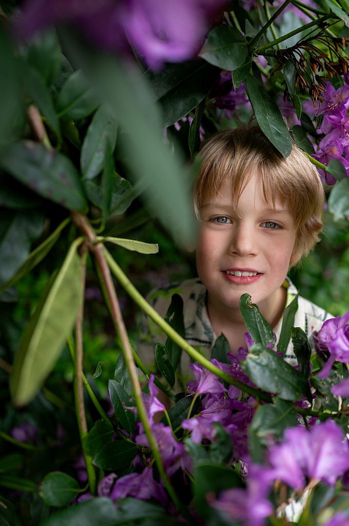 Communicant kijkt tussen paarse bloemen door.