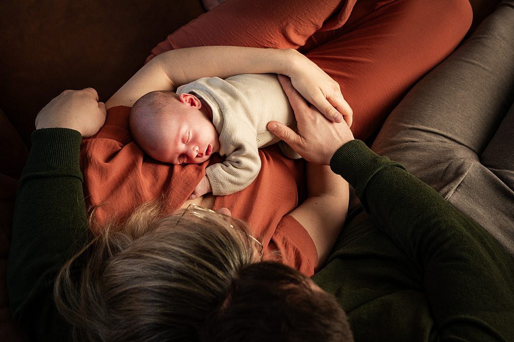 Slapende newborn baby in de armen van mama en papa.