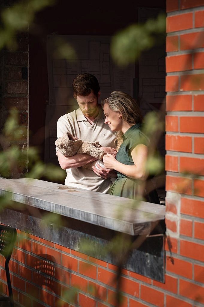 Mama en papa kijkend naar hun baby door het raam