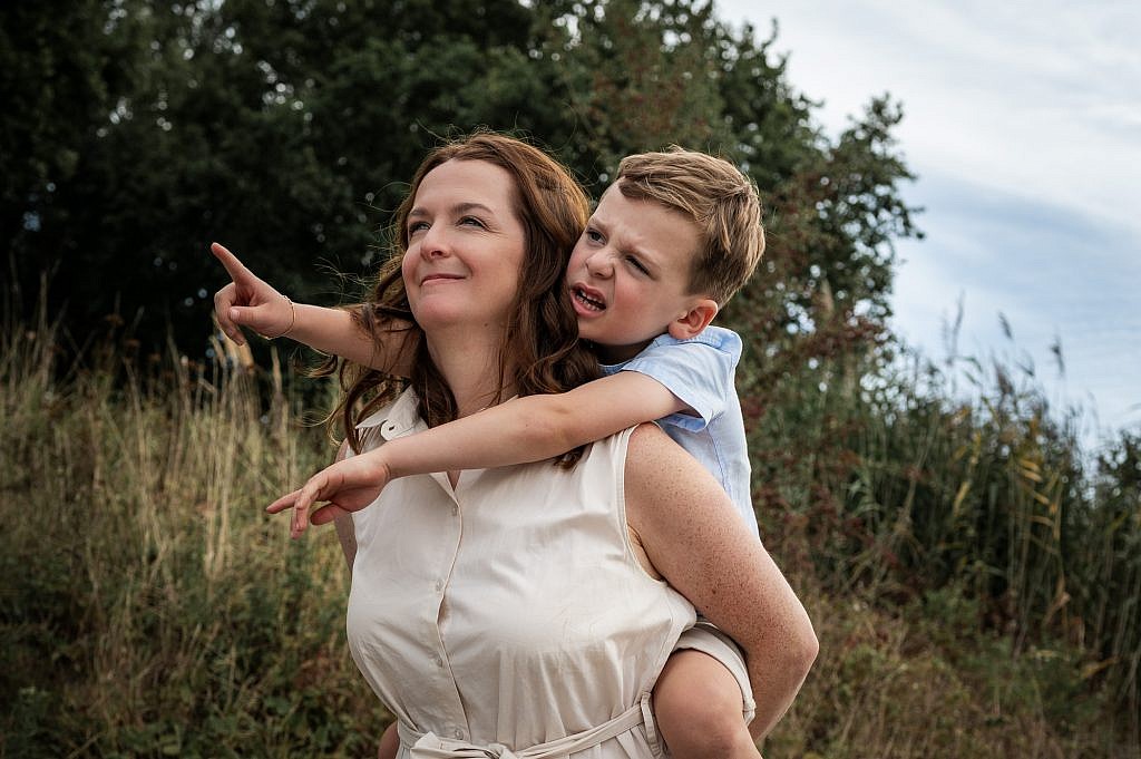 Mama met zoon op de rug die wijst in de lucht