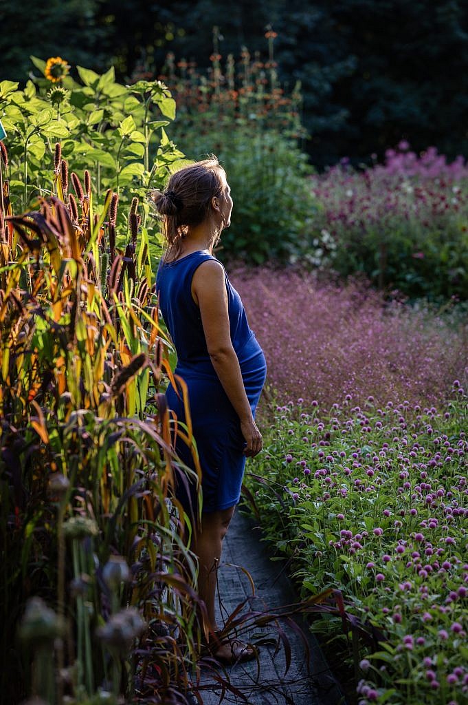 Zwangere vouw met blauw kleedje in een bloemenveld